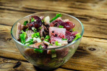 Herring with spices in glass bowl on wooden table