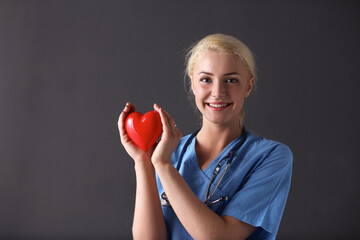 Doctor with stethoscope holding heart, isolated on gray background