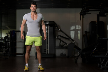 Fototapeta na wymiar Strong Man in Grey T-shirt Background Gym