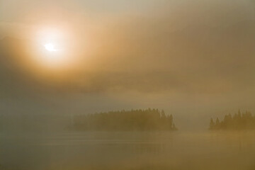 Fog on the mountain lake and the rising sun. Yakutia, lake Darpir.
