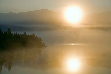Fototapeta na wymiar Fog on the mountain lake and the rising sun. Yakutia, lake Darpir.