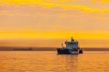 Fototapeta na wymiar Tanker and tugboat on sea early morning just before sunrise.