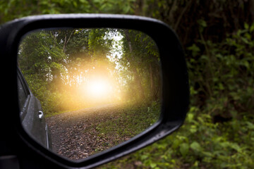 Car on the road in forest view from mirror side of car.