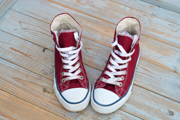 grunge wooden background with red vintage canvas sneakers


