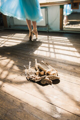 Young ballerina or dancer girl putting on her ballet shoes. Girl in a turquoise ballet skirt. Old...