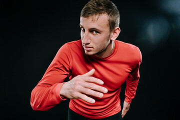 Close up shot of running man sprinting for success on run. Athlete runner training at fast speed at gym. Muscular fit sport model sprinter exercising sprint in red sportswear. Caucasian fitness model