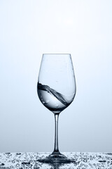 Cleaner and freshness water wave in the wineglass while standing on the glass against light background.