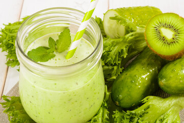 Healthy green smoothie in jar with cucumber, kiwi, salad and spices