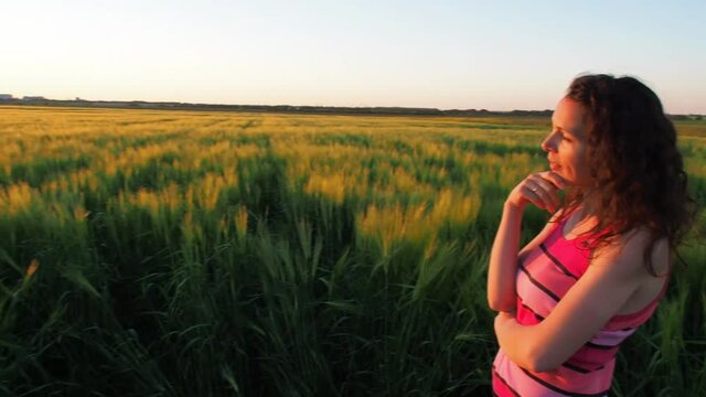 The girl is looking at the sunset. Sunset over the wheat field