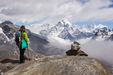 Crédence de cuisine en verre imprimé Ama Dablam Une jeune femme randonneuse avec sac à dos et bâtons de randonnée se tient debout et regarde sur la montagne Ama Dablam. Ciel nuageux. Himalaya, Népal.