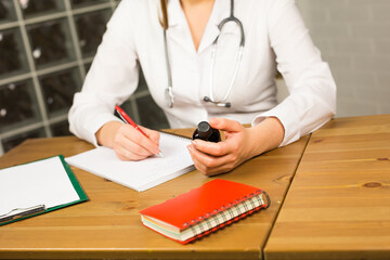 Close-up of doctor writing prescription and holding bottle with pills. Healthcare, medical and pharmacy concept.