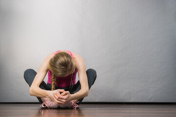 Sad depressed young teenage girl sitting by wall