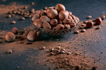Hazelnut, coffee beans and cocoa powder in dark background.