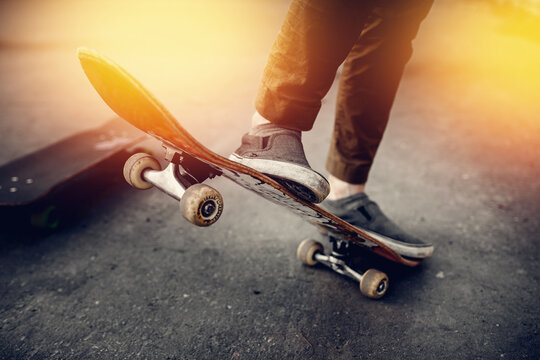 Close-up of a male guy on a skateboard doing trick kicks in shoes. The concept of doing street sports skateboarding. Sunset, toning pictures.