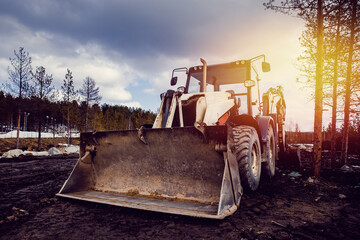 Machine tractor loader on a sky background with a glare from the sun. Concept road construction.