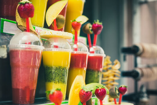 Assortment of fruit smoothie with cocktail tubes in plastic glasses in Prague Czech Republic. Toned image with selective focus