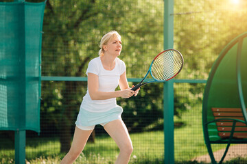 Tennis player playing on the court on a sunny day. Young sport woman training outdoors. Healthy lifestyle concept.