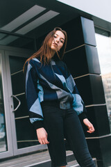 A young and stylish girl in fashionable clothes walks down the street in the city