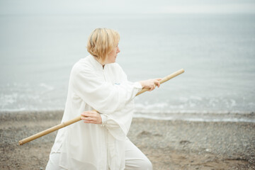 European caucasian adult woman In white clothes practicing Chinese traditional art Taijiquan in...