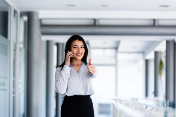 Fototapeta premium Attractive woman talking on phone and showing thums up