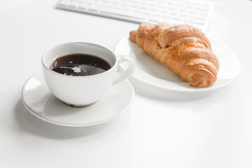 Office lunch with coffee and croissant, keyboard on white table background