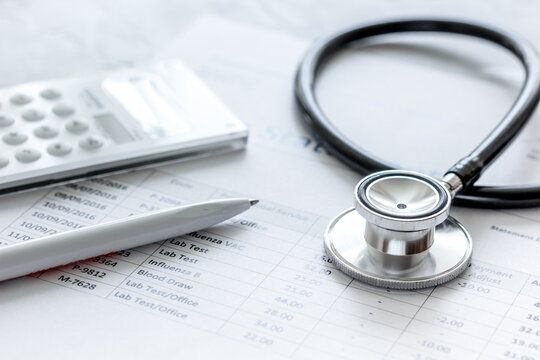 health care costs with billing statement, stethoscope and calculator on stone table