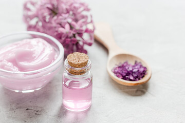 Fototapeta na wymiar spa cosmetic set with lilac flowers stone desk background