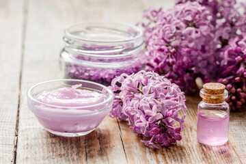 Obraz na płótnie Canvas spa cosmetic set with lilac flowers wooden desk background