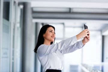 Beautiful woman at business building taking selfie