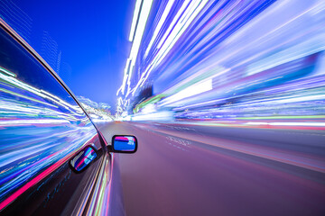 Obraz premium View from Side of Car moving in a night city, Blured road with lights with car on high speed. Concept rapid rhythm of a modern city.