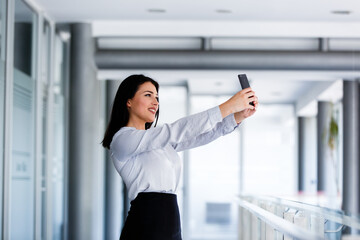 Beautiful woman at business building taking selfie