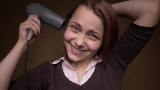 Emotional happy teenager girl make funny faces while drying her hair. Slow motion