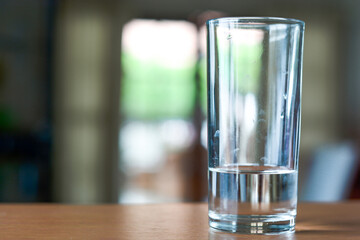 Glass of water on a wooden desk and living room background