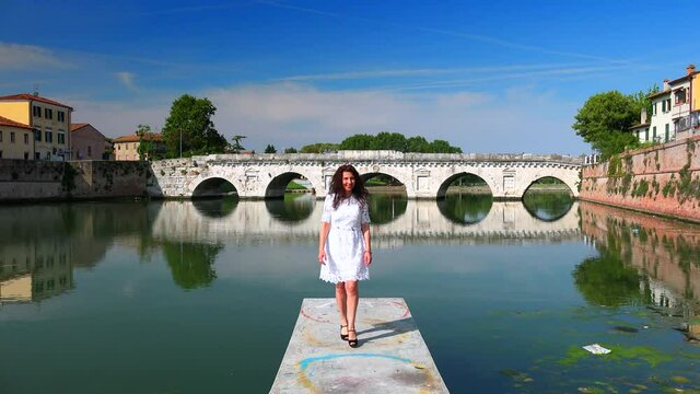 smiling woman on pier with cityscape of Rimini in background