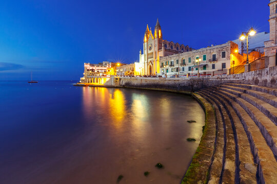 Balluta Bay and Neo-Gothic Church of Our Lady of Mount Carmel, Balluta parish church, during evening blue hour, Saint Julien, Malta