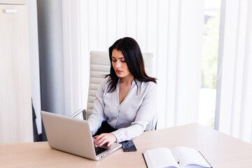 Attractive woman sitting in office and typing on her laptop