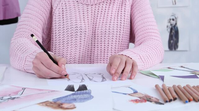 Designer dress hands create beautiful drawings with pencils for the clothing magazine. Close up