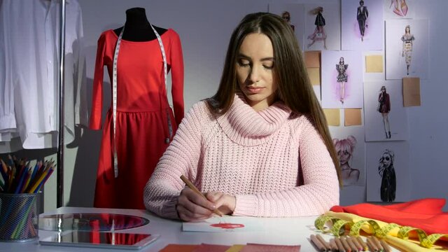 Fashion designer draws a sketch of a red dress, workshop