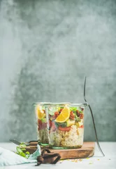 Poster Healthy salad with quionoa, avocado, dried tomatoes, basil, mint, orange in glass jars on wooden board, grey wall at background, selective focus, copy space. Clean eating, vegan, detox food concept © sonyakamoz