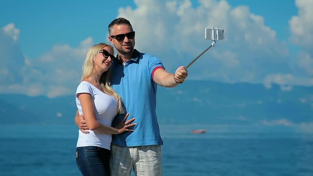 Happy young couple taking mobile photos selfie on background of the sea.Happy vacation