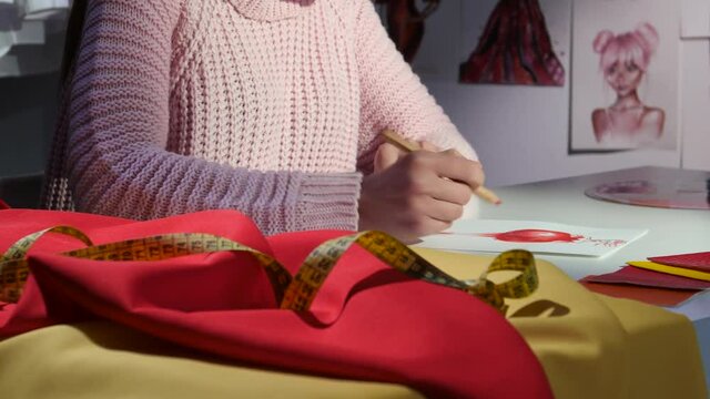 Designer's hands draw a sketch on the walls hang a lot of other sketches. Close up