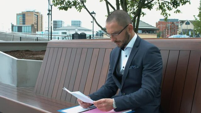A Marketing Director Sitting On A Bench And Checking Documentation