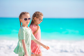 Adorable little girls having fun together on white beach