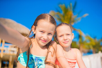 Fototapeta na wymiar Adorable little girls playing in outdoor swimming pool. Cute kids take selfie.