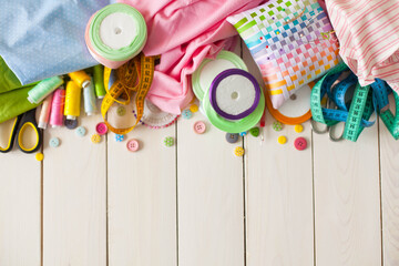 Rolls of colored fabric on a white background. Spools with colored thread on a platter. White...
