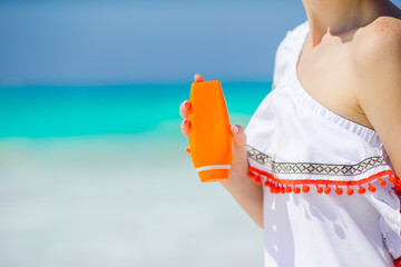 Closeup suncream bottle in female hands on the beach