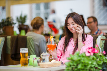 Beautiful woman sitting in a cafe outdoor. Happy tourist enjoy european holidays at openair restaraunt