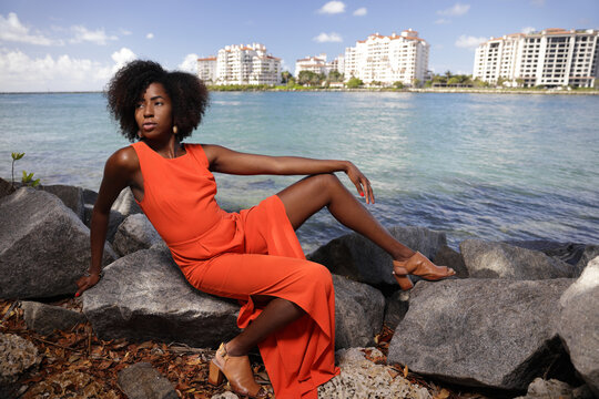 Stock image of a young black woman posing in the park in an orange jumpsuit