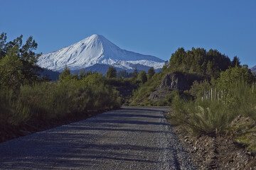 Snow capped peak of Antuco Volcano (2,979 metres) rising above a gravel road in Laguna de Laja...