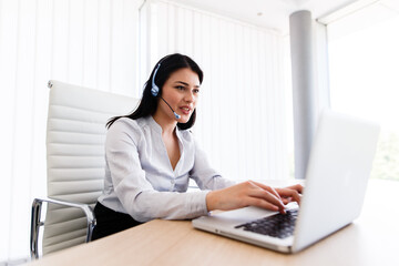 Attractive woman talking with customer at her work desk with headset